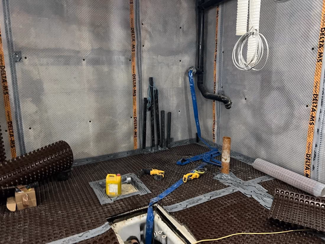 Basement waterproofing and services stage with dimpled membrane and conduit on concrete walls