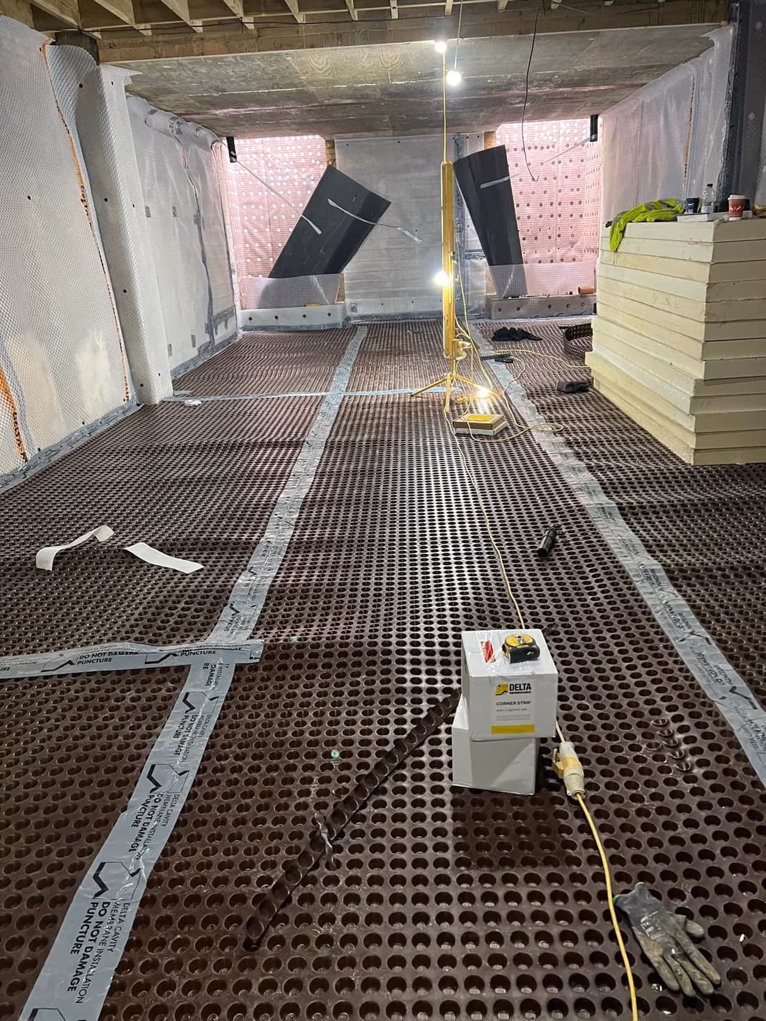 Basement waterproofing with dimpled membrane and insulation boards ahead of fit-out