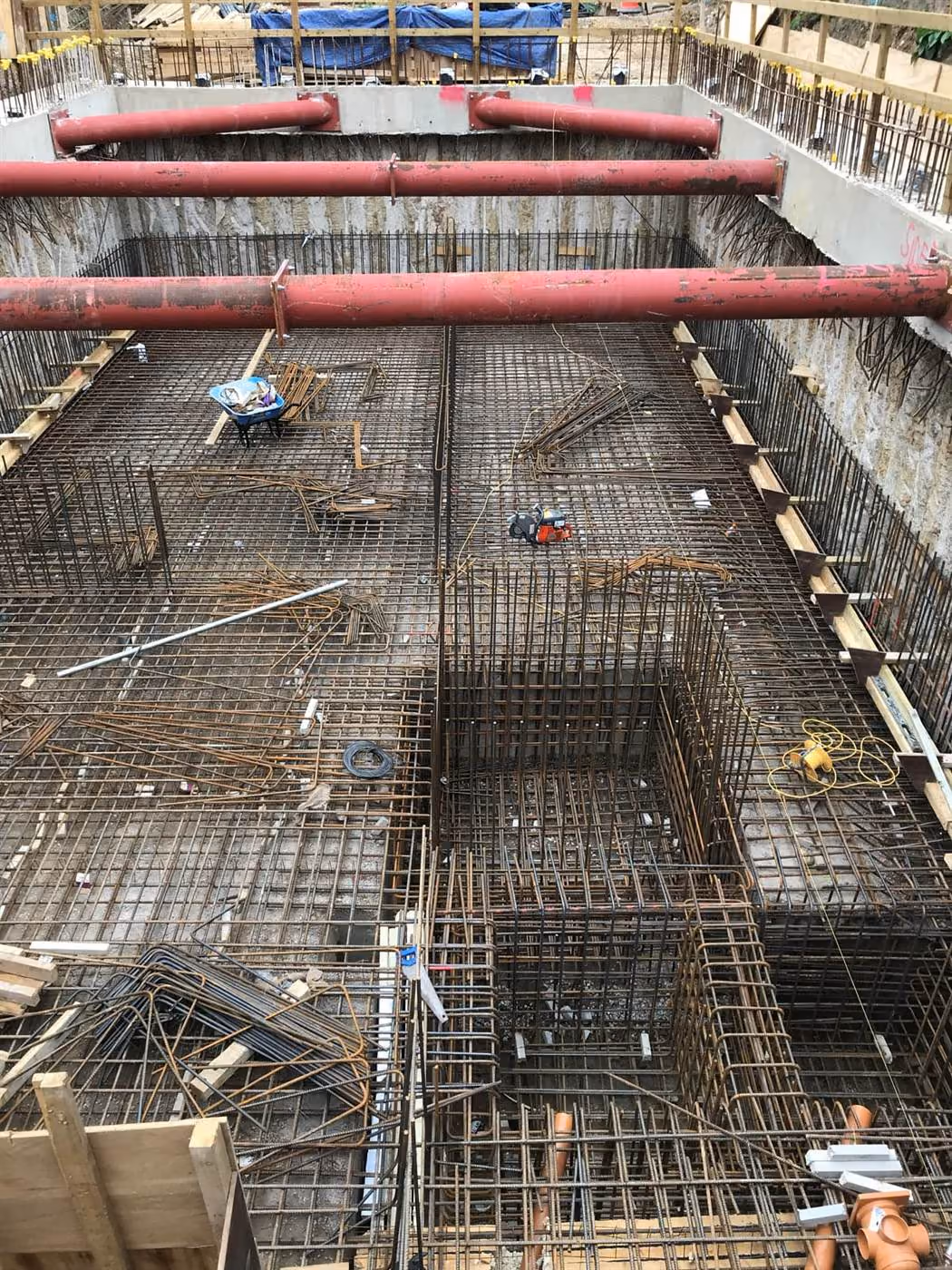 Reinforced concrete basement under construction in London, with steel reinforcement mat and concrete pump lines