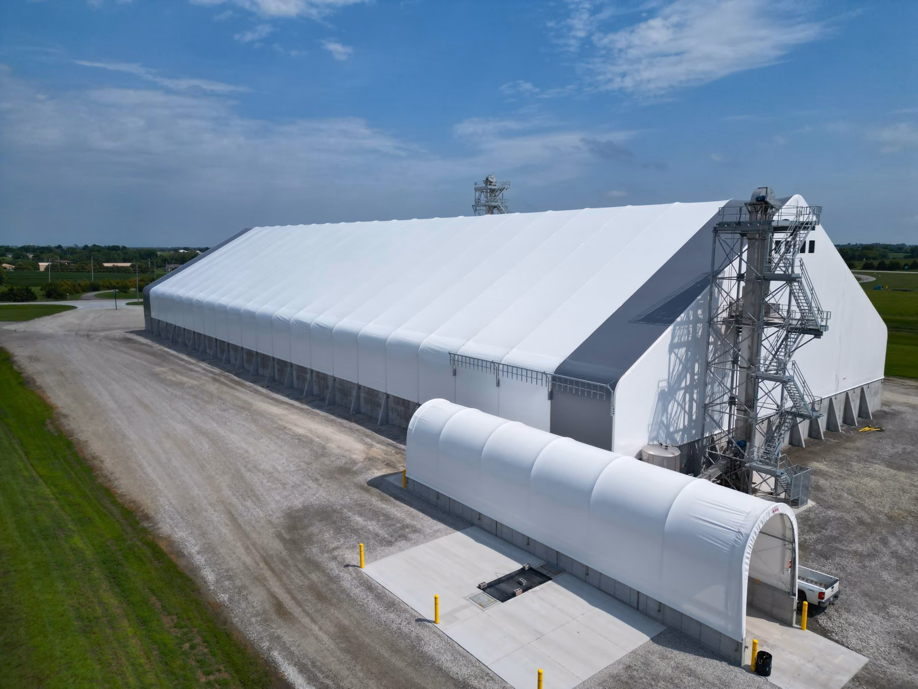 Aerial view of a large white Calhoun engineered fabric building with a steel-frame roof and bulk-handling tower at a rural commercial site