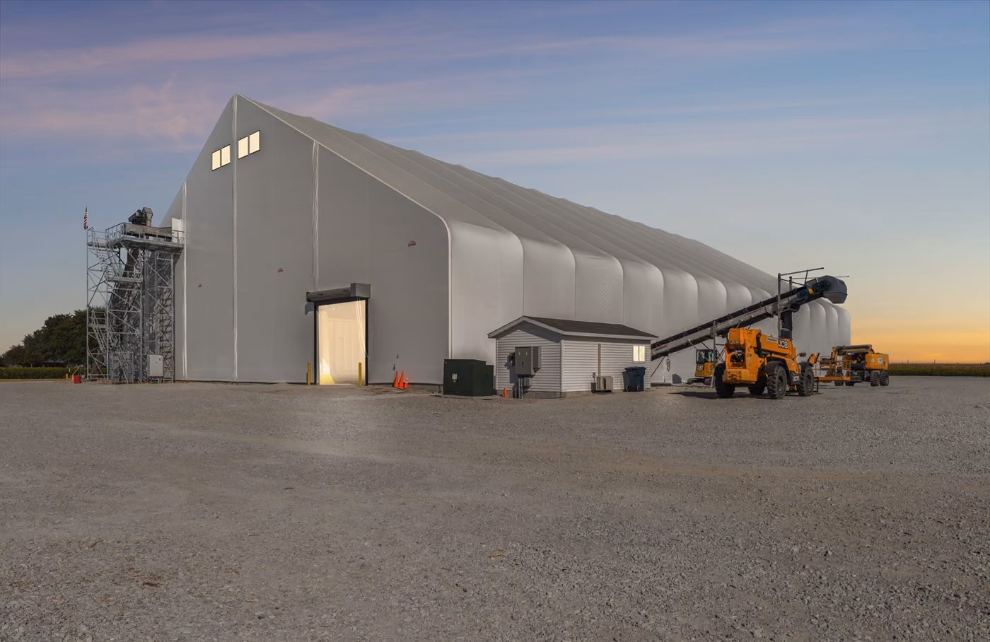 Calhoun fabric fertiliser storage building with loading equipment at dusk