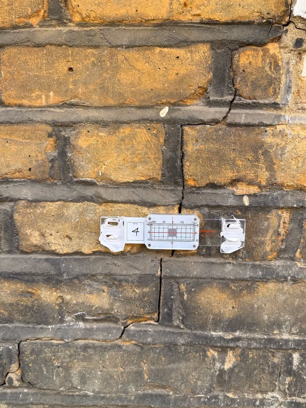 Crack monitor gauge fitted across a crack in London stock brickwork to assess structural movement before repair
