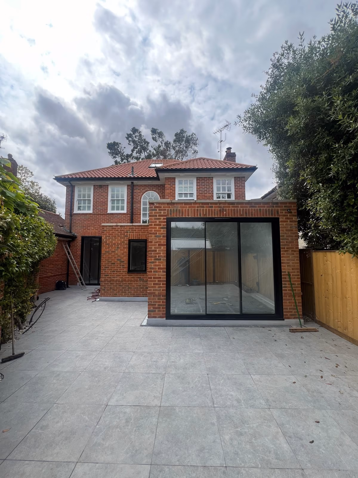 Completed single-storey brick rear extension with full-width black-framed sliding doors and a new patio, Richmond upon Thames