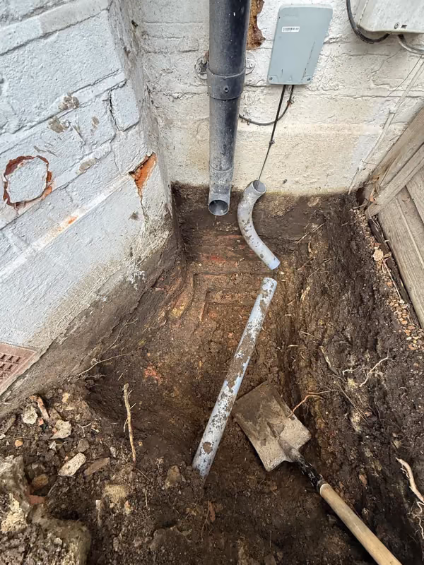 Trial pit exposing the foundation beside a downpipe at a London property