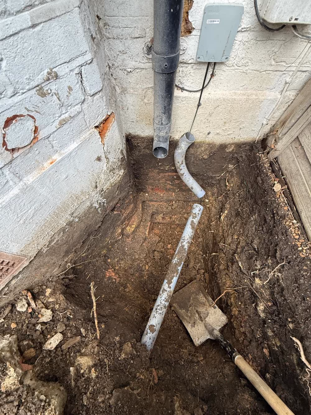 Trial pit exposing the foundation beside a downpipe at a London property