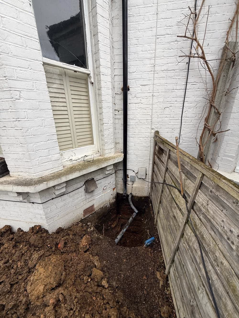 Open trial pit excavated along the base of a wall to inspect the foundation and ground
