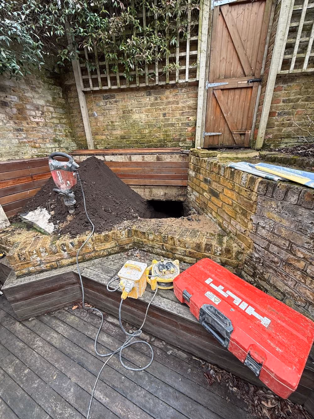 Open trial pit beside decking exposing the foundation for inspection