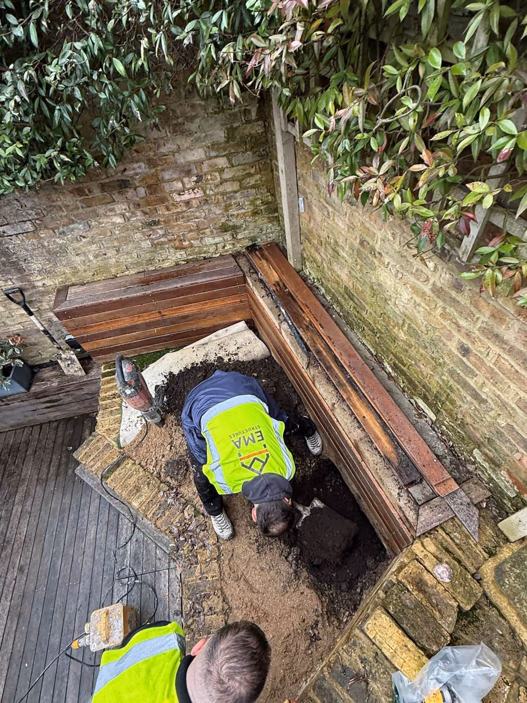 Trial pit investigation by EMA Structures beside a London property, with the site team excavating to expose the foundation for engineer inspection